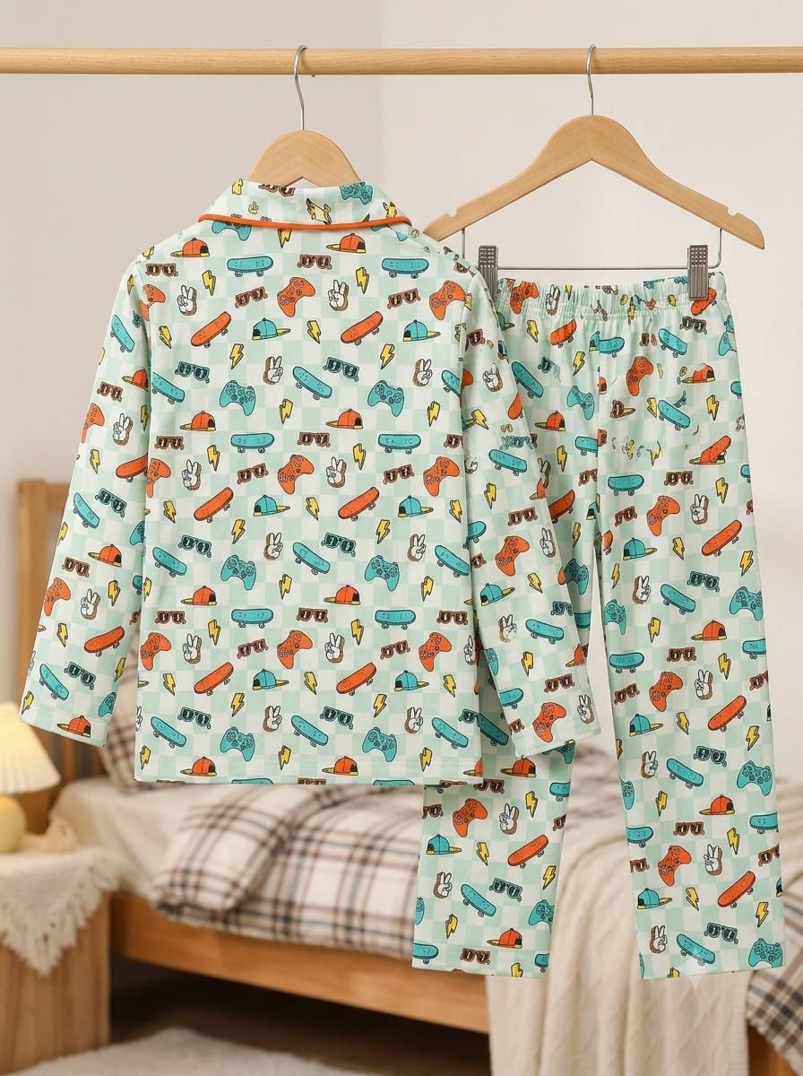 A two-piece children's pajama set hanging on wooden hangers, featuring a light mint green base with a colorful cartoon pattern of toy cars, rockets, and lightning bolts. The set includes a long-sleeve top and matching pants, shown against a softly blurred bedroom background.