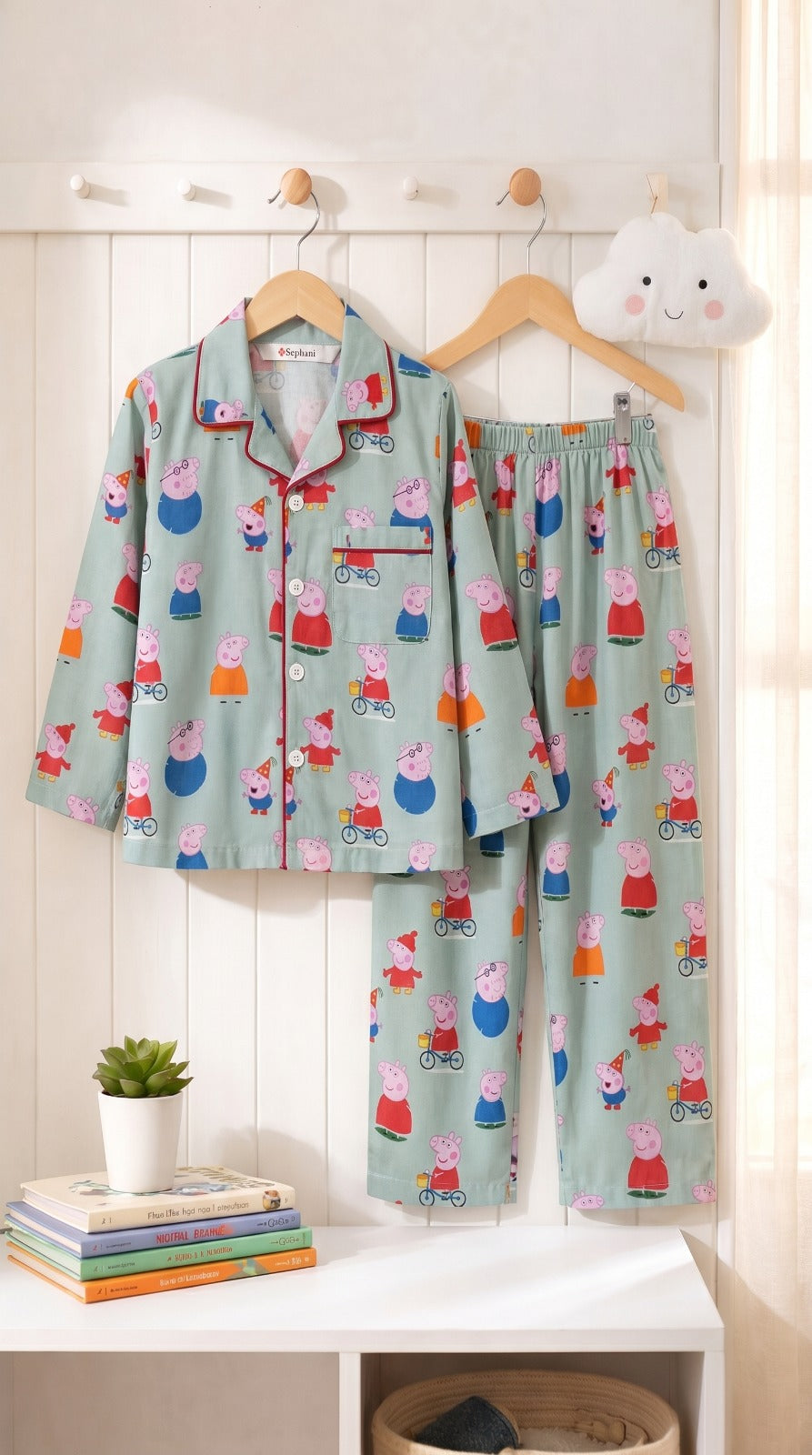 Children's pajama set with Peppa Pig design on a hanger against a white wall.